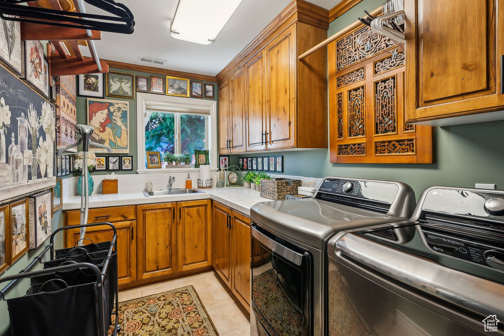 Laundry area featuring cabinet space, washer and dryer, and light tile patterned floors