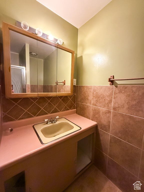 Bathroom featuring tile walls, vanity, a wainscoted wall, and an enclosed shower