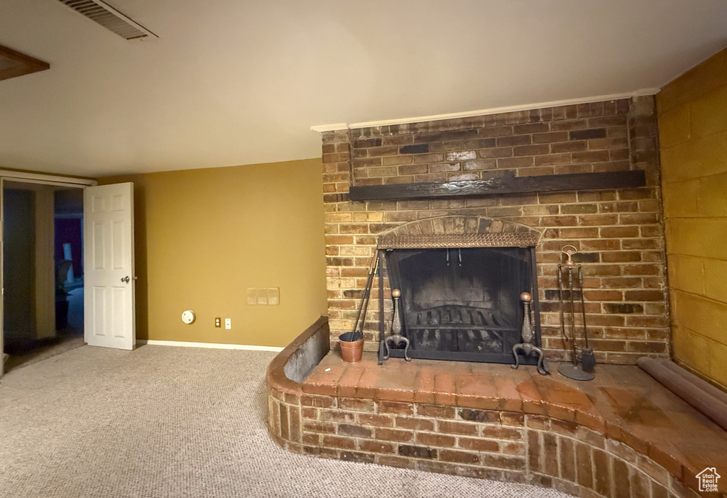 Detailed view of a brick fireplace, carpet flooring, and baseboards