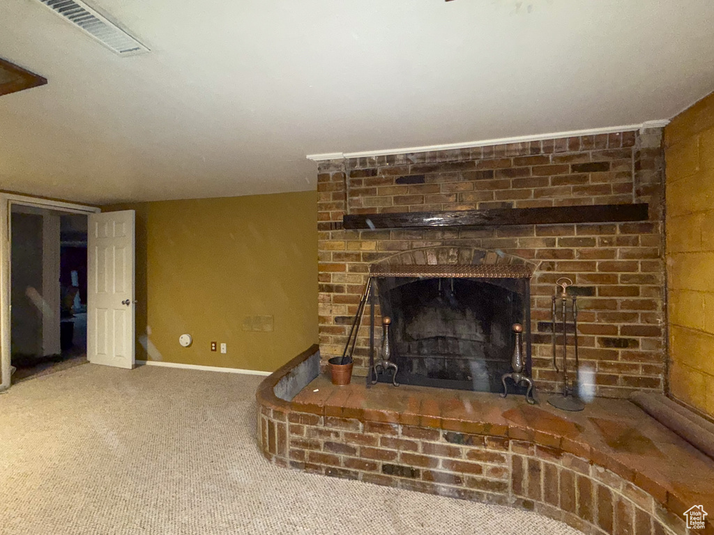 Unfurnished living room with a brick fireplace, carpet flooring, and baseboards