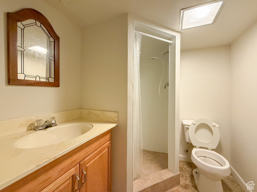 Bathroom featuring vanity, toilet, a shower with shower curtain, and baseboards