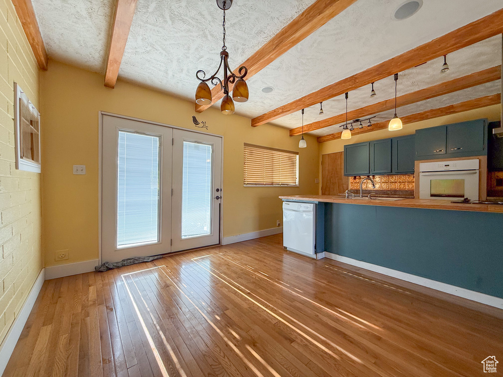 Kitchen featuring white appliances, a chandelier, beam ceiling, hardwood / wood-style flooring, and pendant lighting