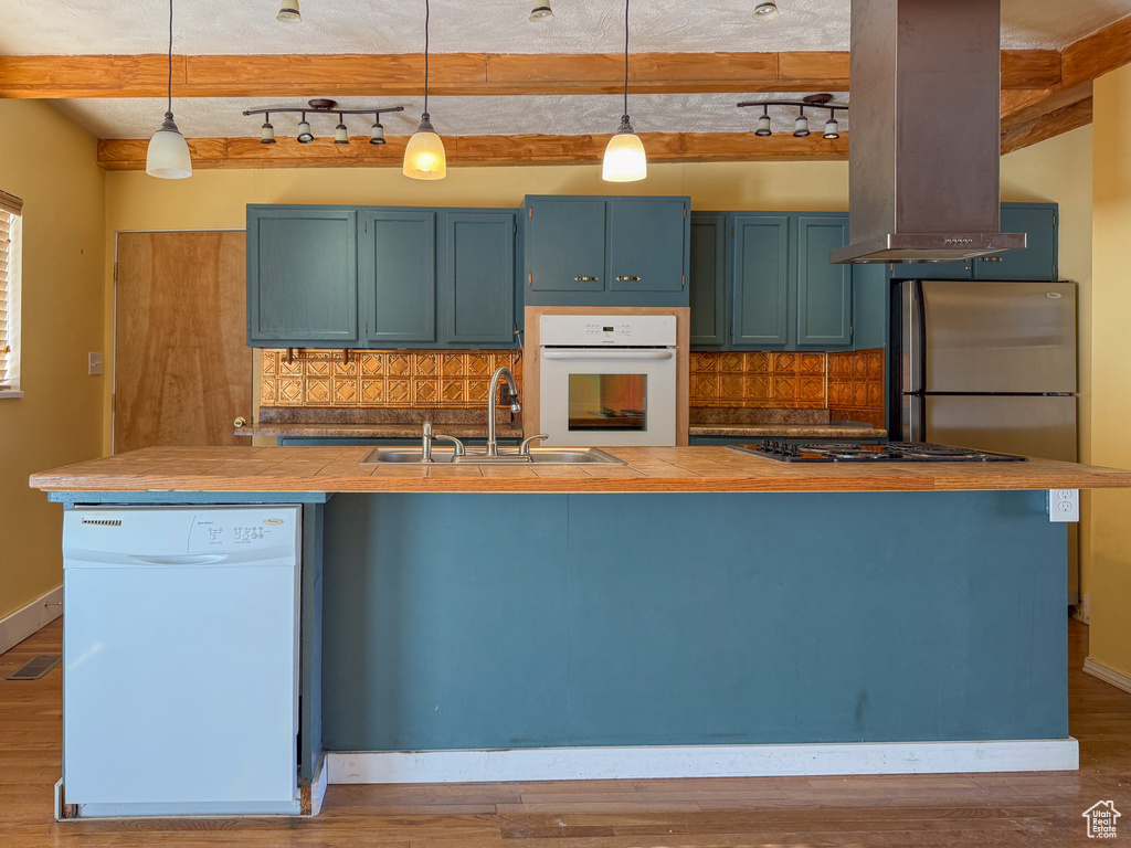 Kitchen featuring white appliances, a sink, decorative backsplash, blue cabinets, and beam ceiling