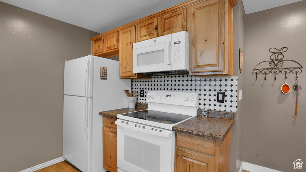 Kitchen featuring white appliances, backsplash, and baseboards