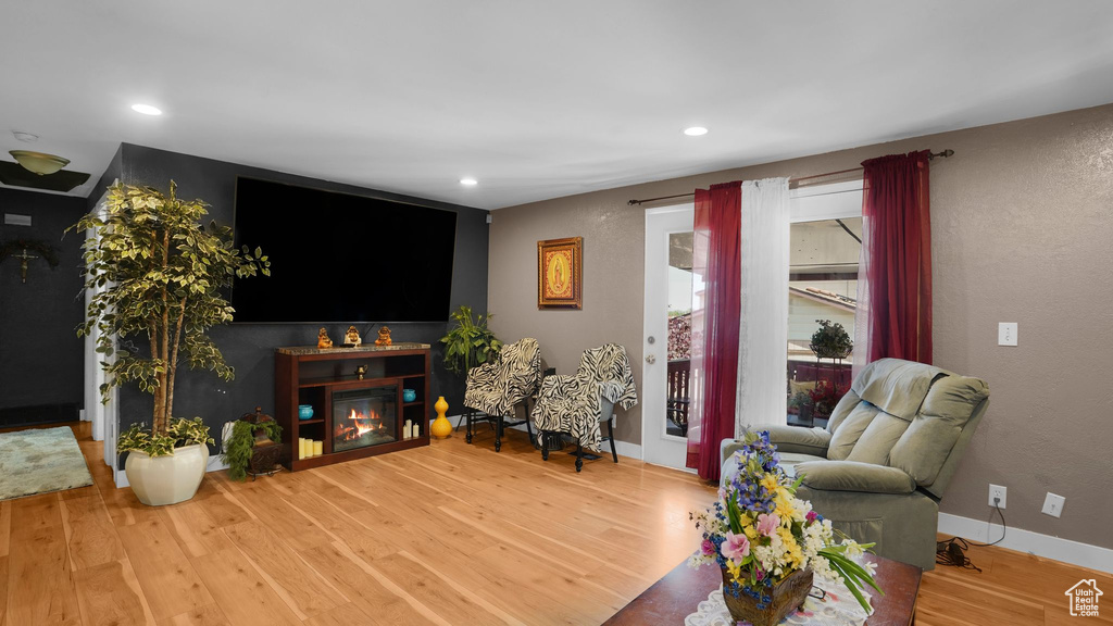 Living area with wood finished floors, a glass covered fireplace, baseboards, recessed lighting, and a textured wall