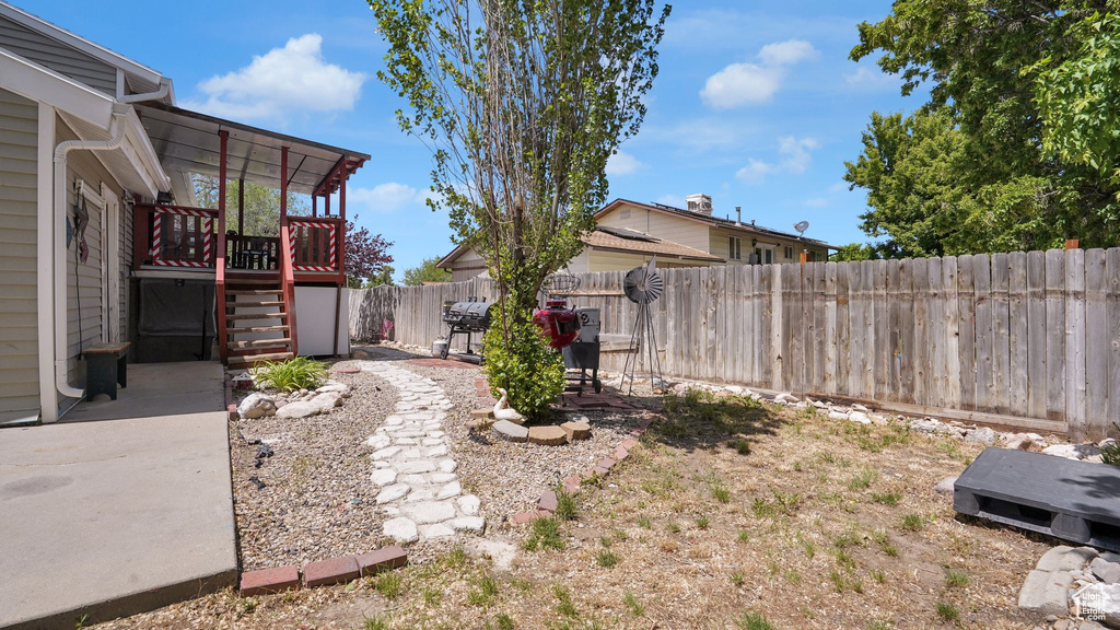 Fenced backyard with stairs, a wooden deck, and a patio area
