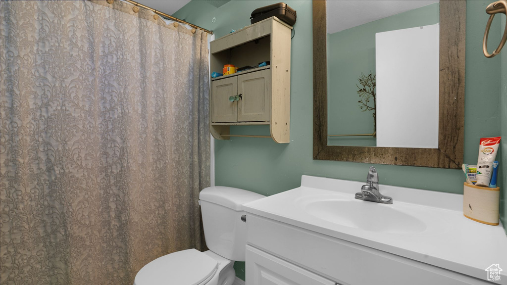 Bathroom with toilet, vanity, and a shower with shower curtain