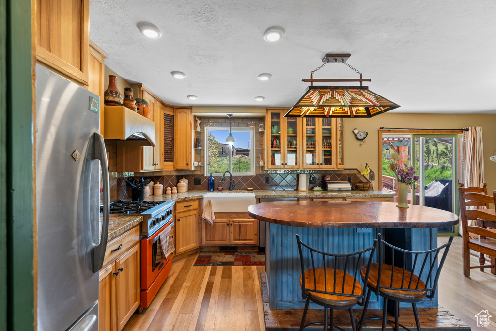 Kitchen with appliances with stainless steel finishes, a sink, plenty of natural light, and a breakfast bar