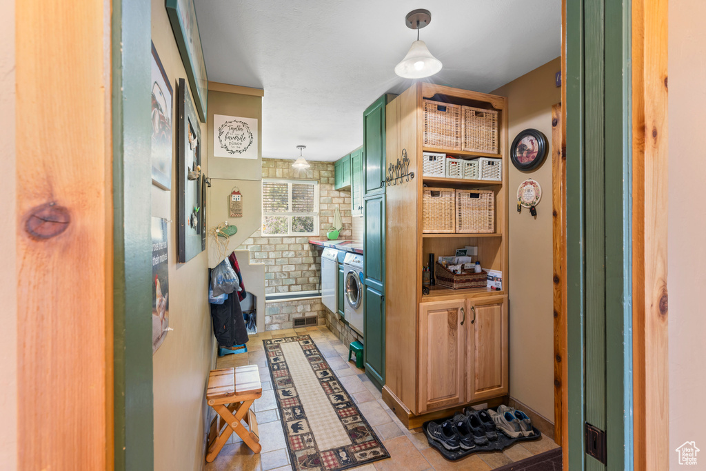 Kitchen featuring light tile patterned flooring, washing machine and clothes dryer, and decorative light fixtures