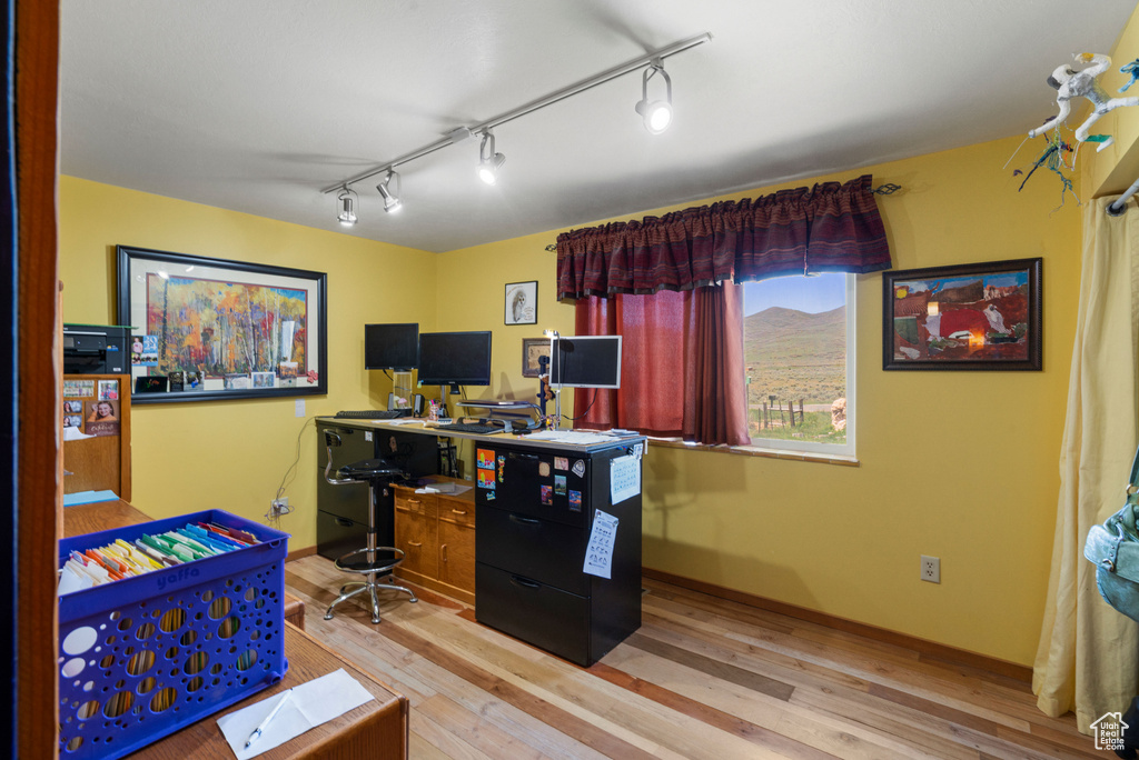 Office with wood finished floors, baseboards, and rail lighting