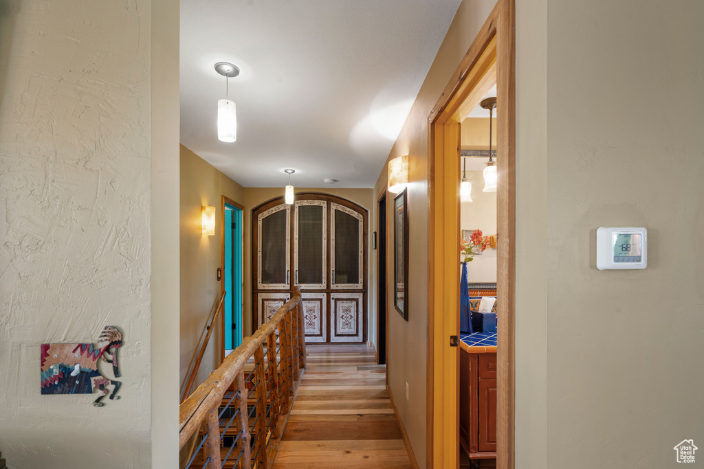 Corridor with an upstairs landing and light wood-style flooring
