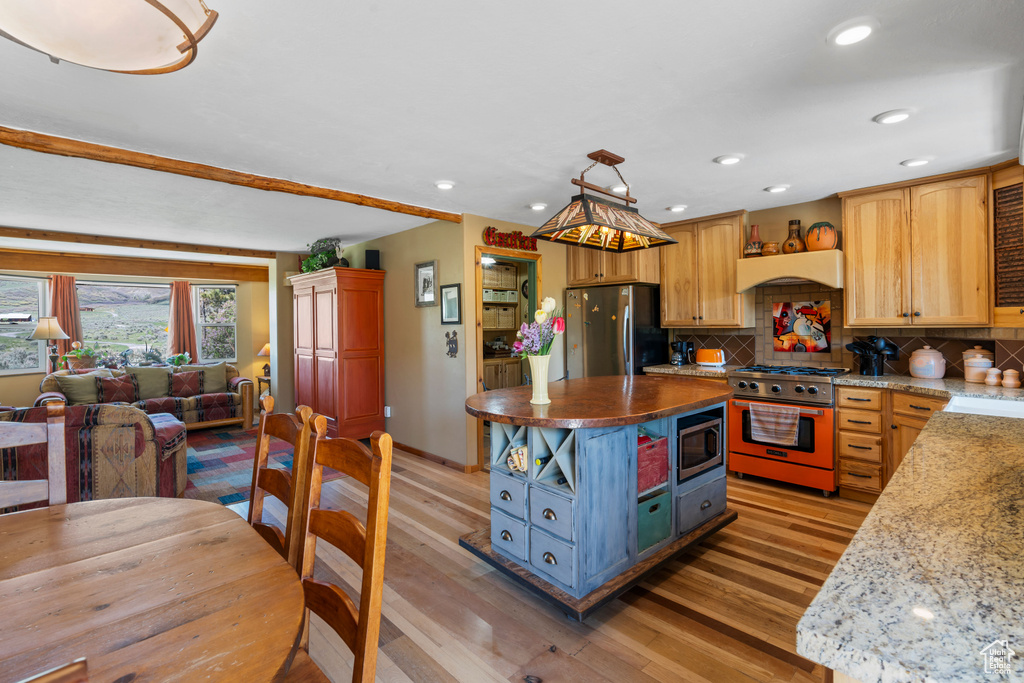 Kitchen with appliances with stainless steel finishes, light wood-style floors, backsplash, recessed lighting, and open floor plan