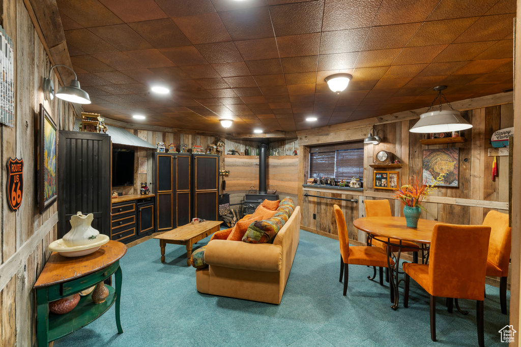 Carpeted living area with a wood stove and wood walls