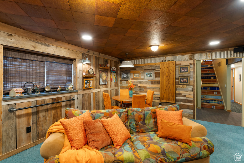Carpeted living room featuring wood walls, stairs, and recessed lighting