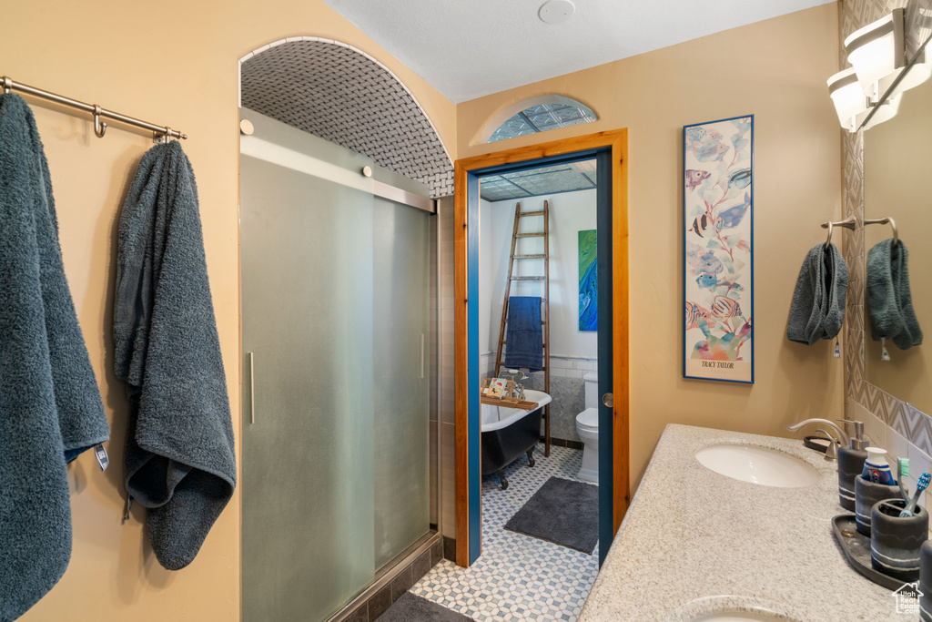 Bathroom featuring a stall shower, double vanity, and toilet