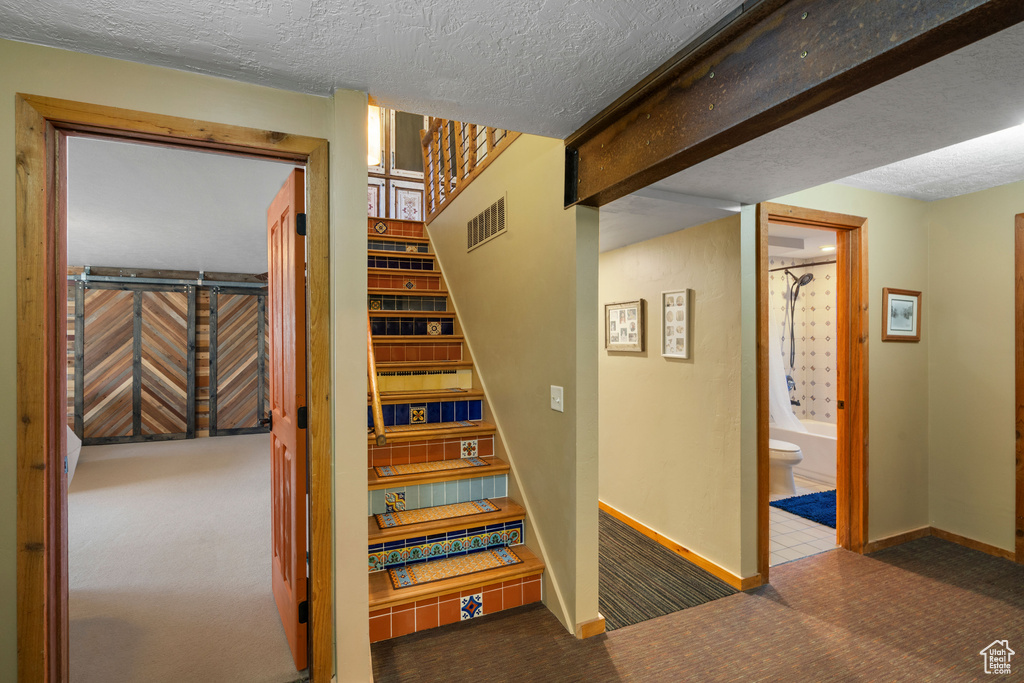 Stairs with carpet flooring, a textured ceiling, and baseboards