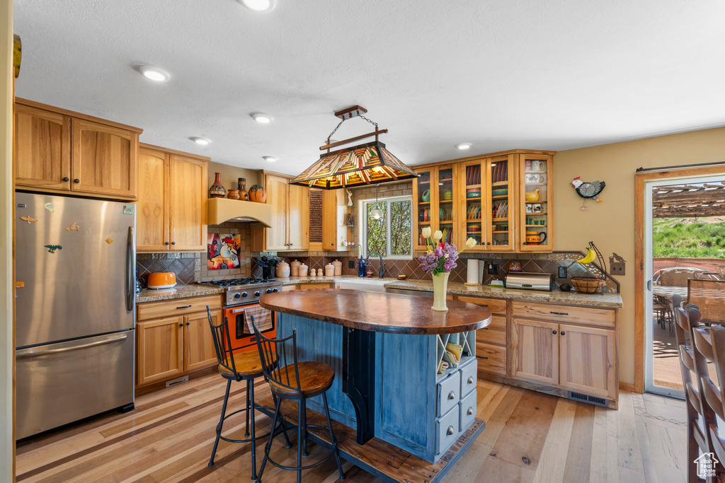 Kitchen featuring appliances with stainless steel finishes, plenty of natural light, light wood-style floors, tasteful backsplash, and recessed lighting