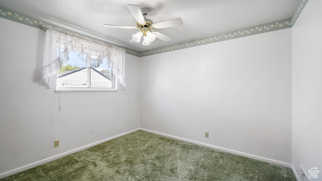 Carpeted empty room with baseboards and a ceiling fan