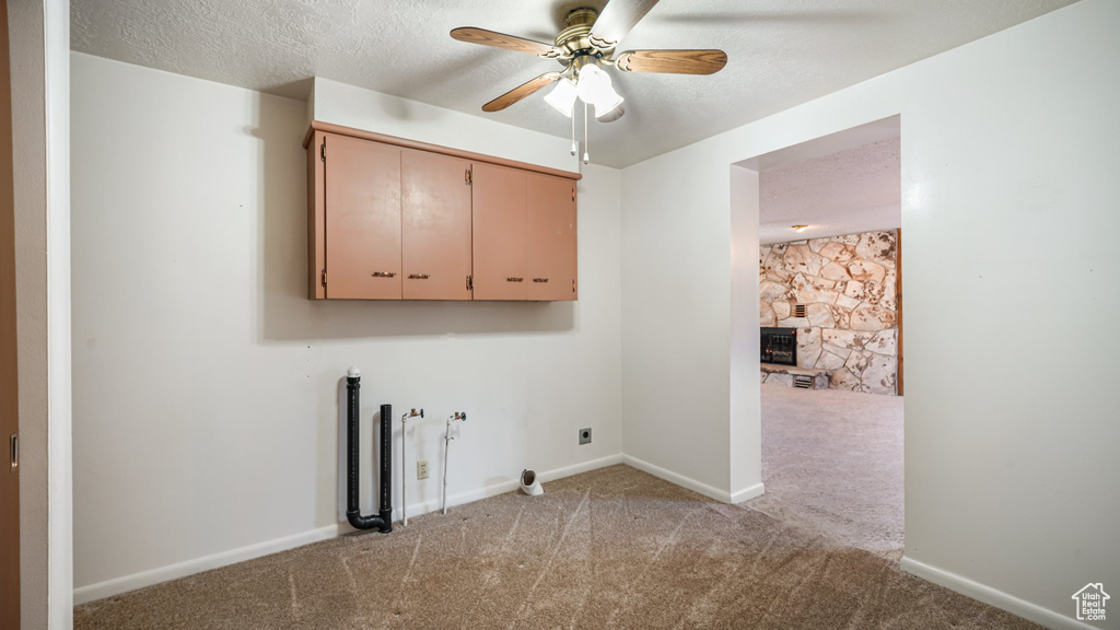 Laundry room with cabinet space, hookup for an electric dryer, a ceiling fan, light carpet, and a fireplace