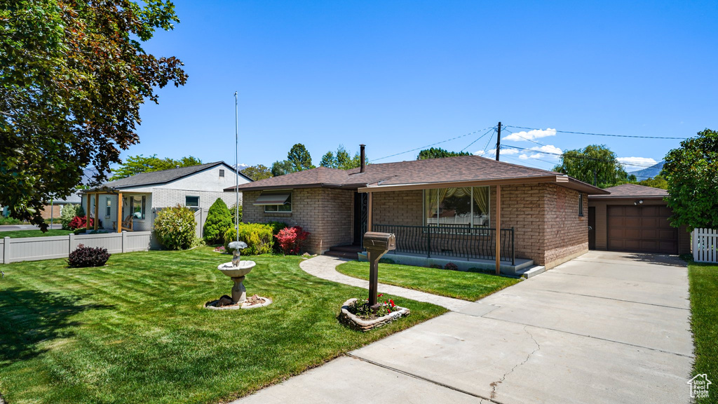 View of front of house featuring covered porch, brick siding, driveway, and an outdoor structure