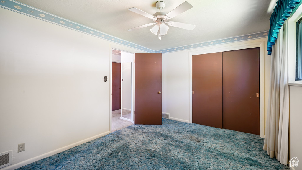 Unfurnished bedroom featuring carpet flooring, a closet, baseboards, and ceiling fan