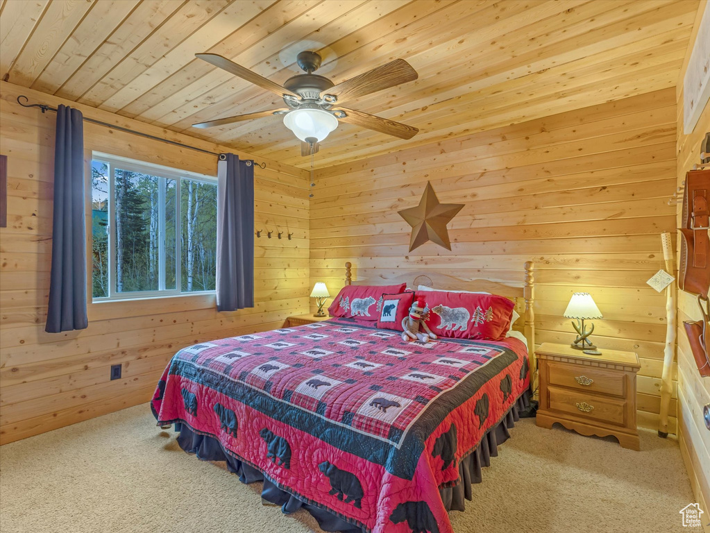 Bedroom featuring wood ceiling, carpet flooring, wood walls, and a ceiling fan