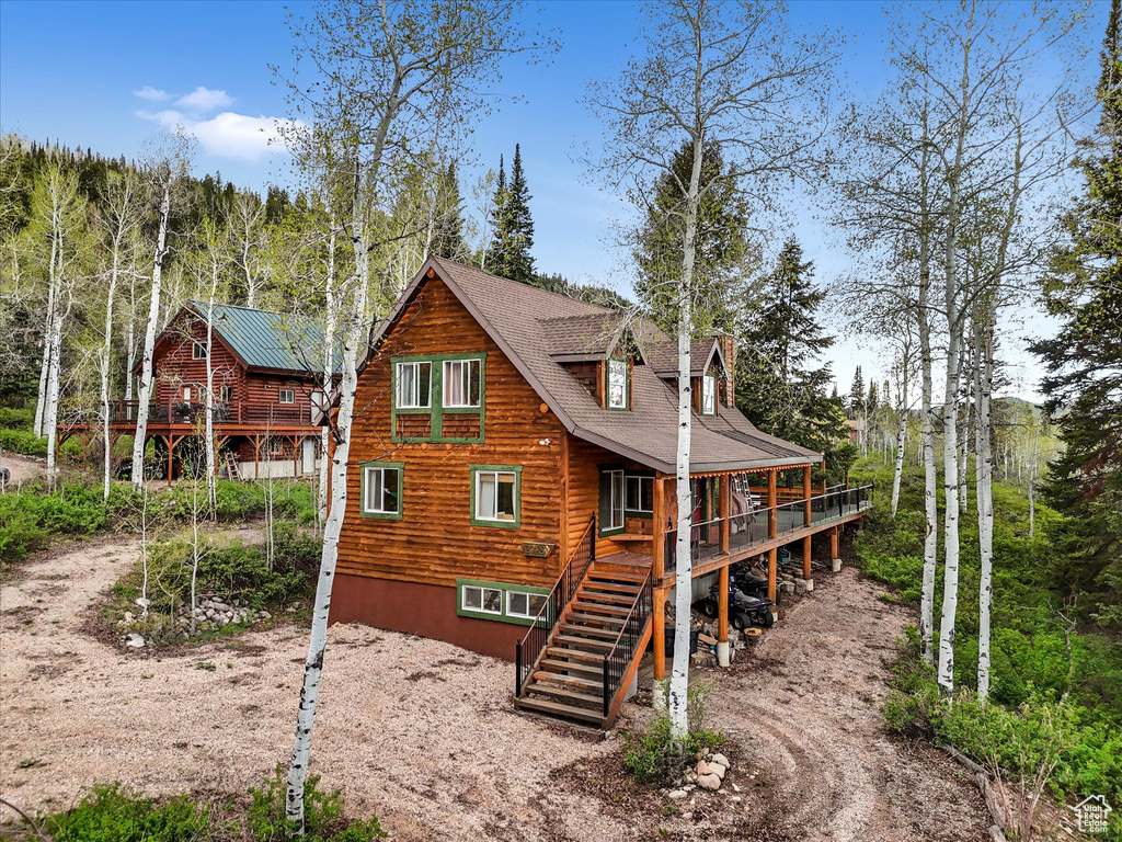 Rear view of property with stairs and dirt driveway