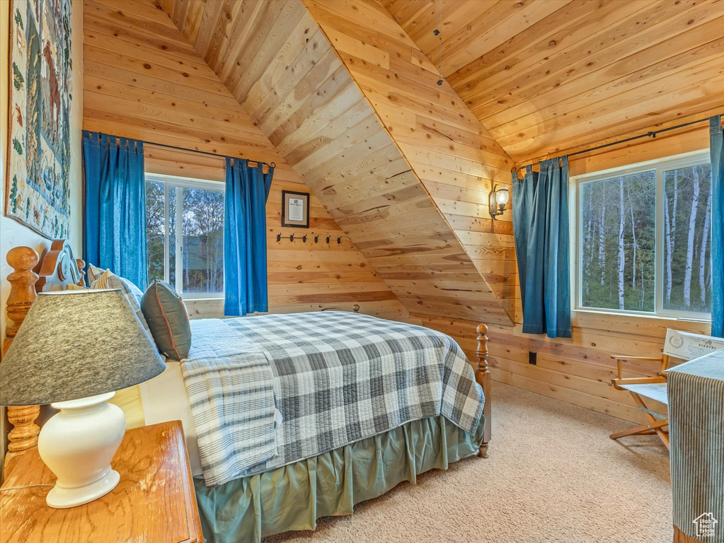 Bedroom with lofted ceiling, wood ceiling, wood walls, and carpet