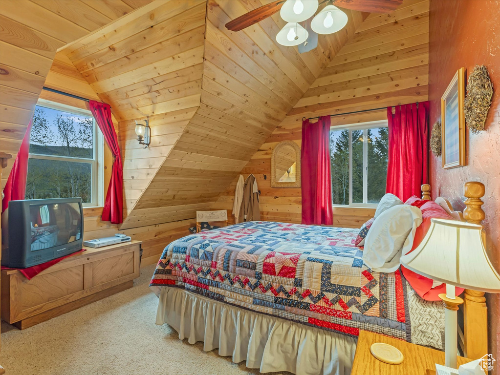 Bedroom featuring multiple windows, lofted ceiling, wood walls, wooden ceiling, and carpet flooring