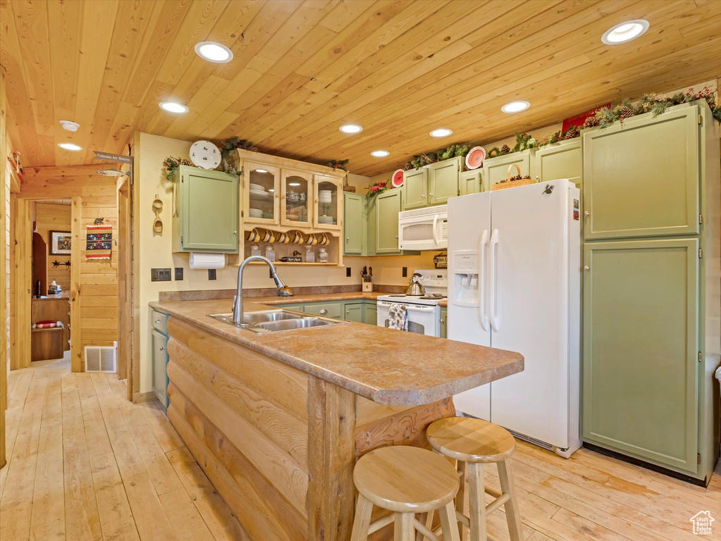 Kitchen featuring green cabinets, white appliances, a sink, recessed lighting, and light wood-style floors