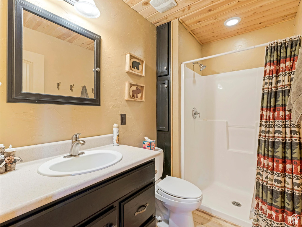 Full bath featuring wood ceiling, a textured wall, a shower stall, vanity, and toilet