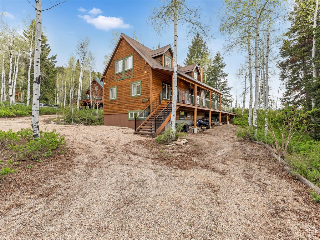 Rear view of property featuring stairway, a deck, and dirt driveway