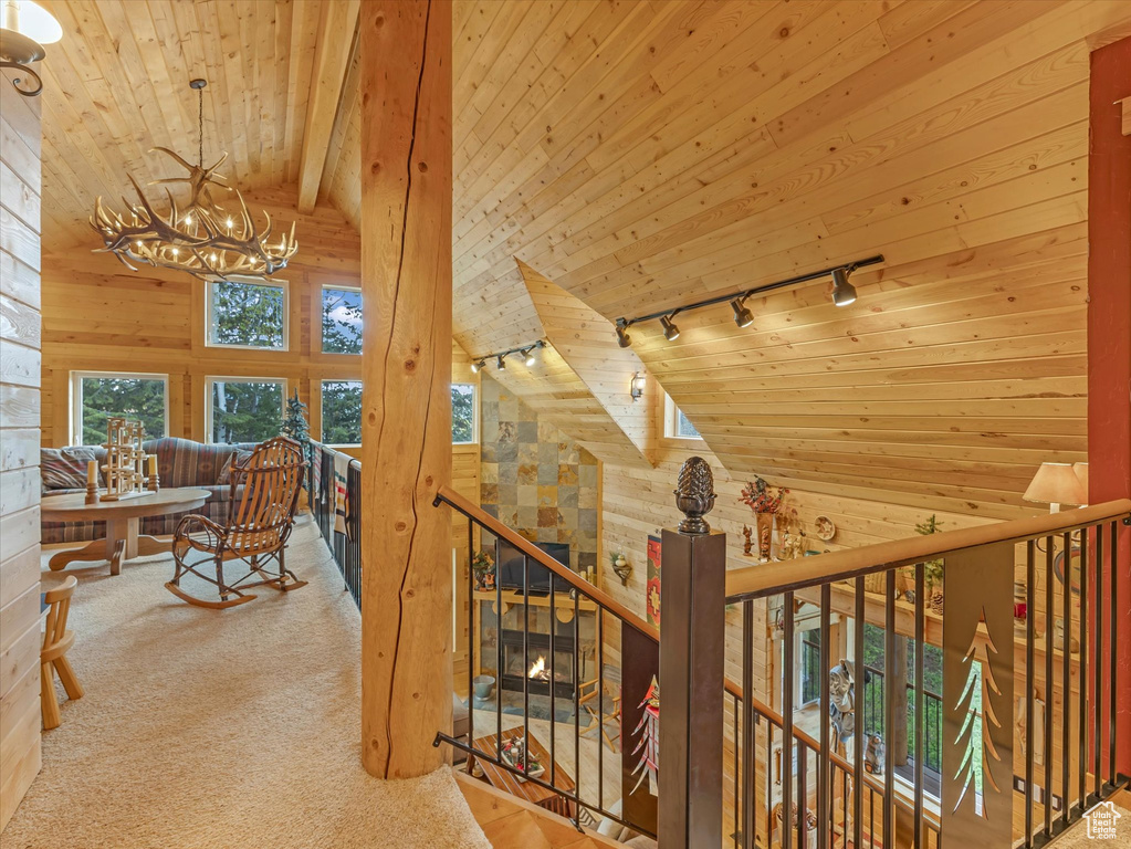 Corridor featuring track lighting, wood ceiling, an upstairs landing, vaulted ceiling, and a chandelier