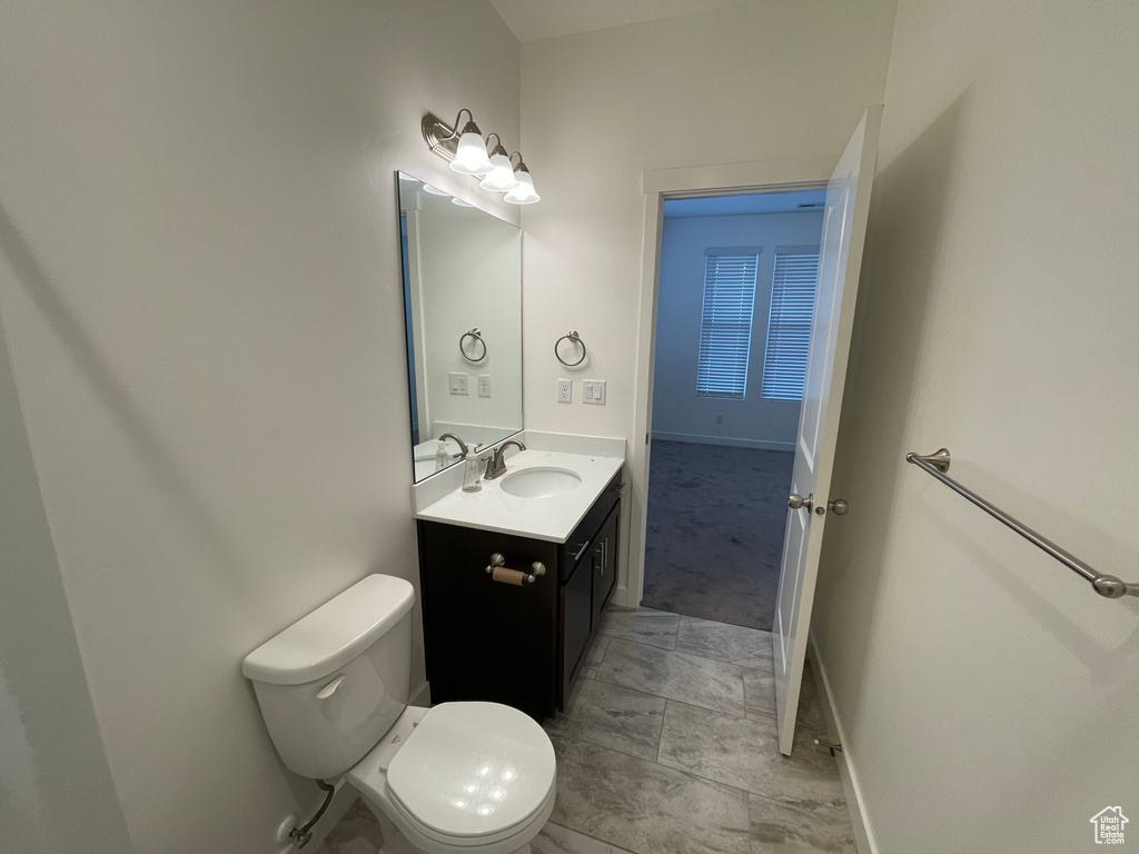 Bathroom featuring vanity, toilet, and baseboards