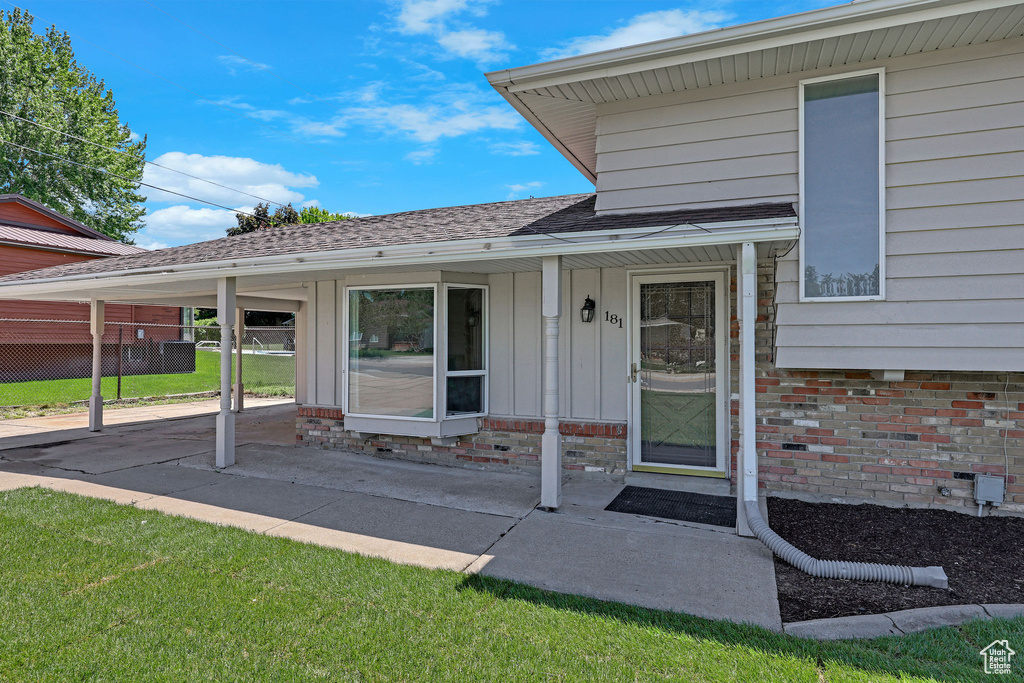 View of exterior entry featuring board and batten siding and a shingled roof