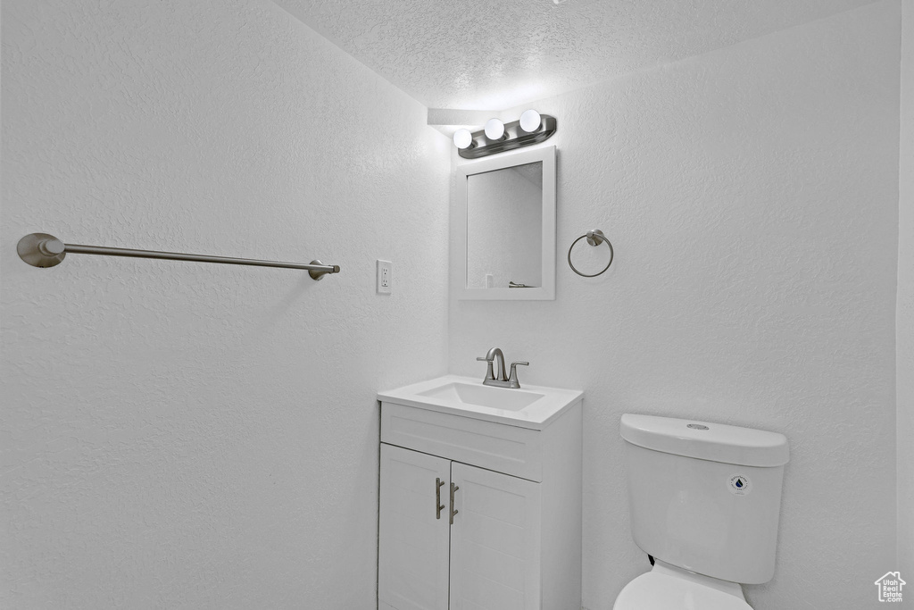 Bathroom featuring vanity, toilet, and a textured ceiling