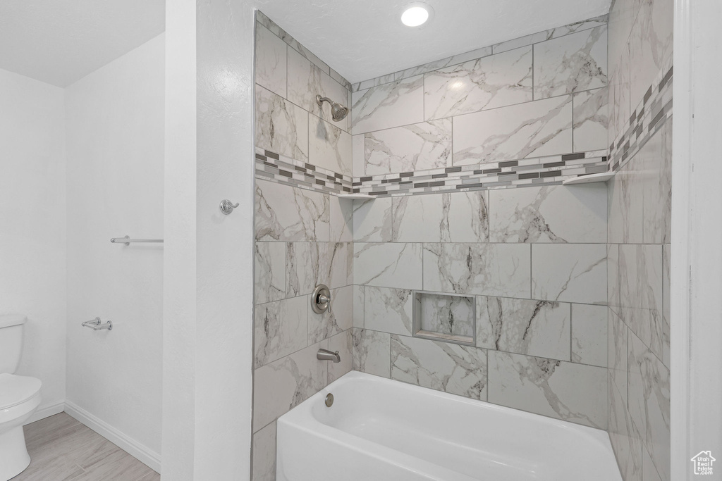 Bathroom featuring toilet, washtub / shower combination, and baseboards