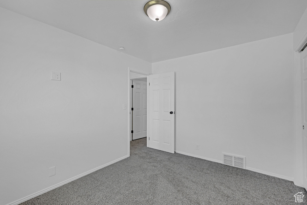 Carpeted spare room featuring baseboards