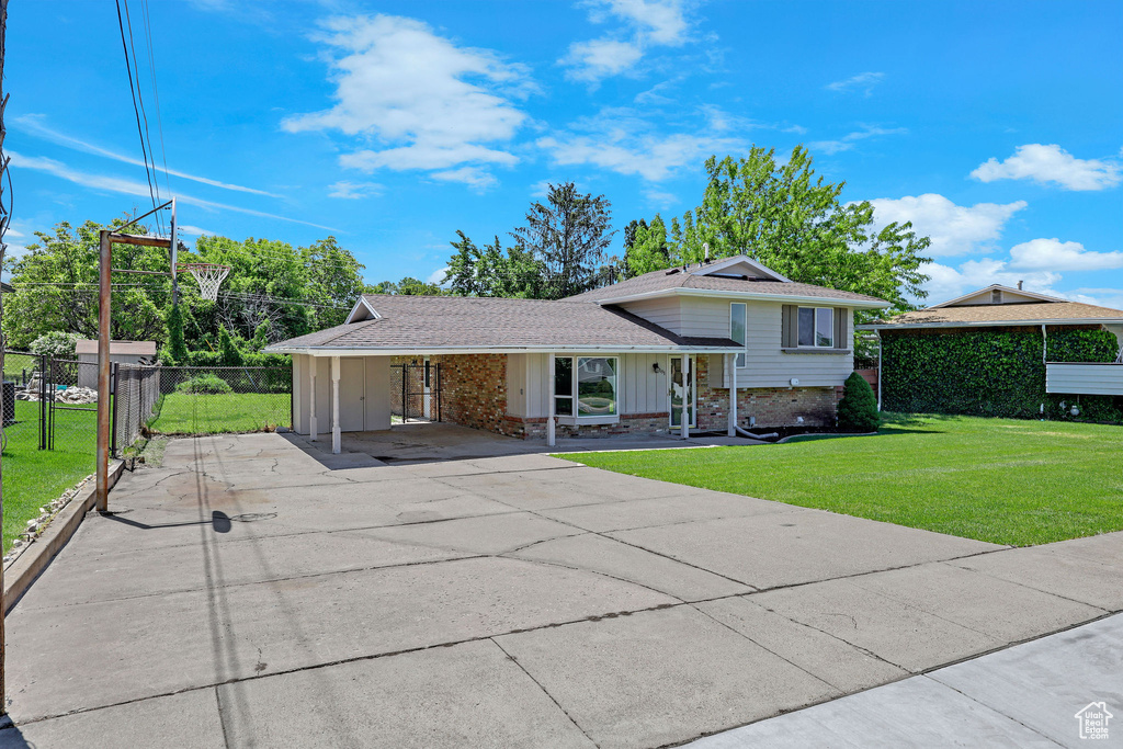 Split level home with driveway, board and batten siding, a shingled roof, and an attached carport