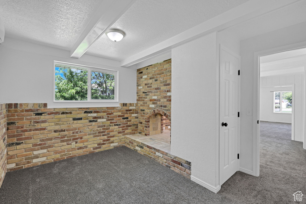 Carpeted spare room with a textured ceiling and beam ceiling