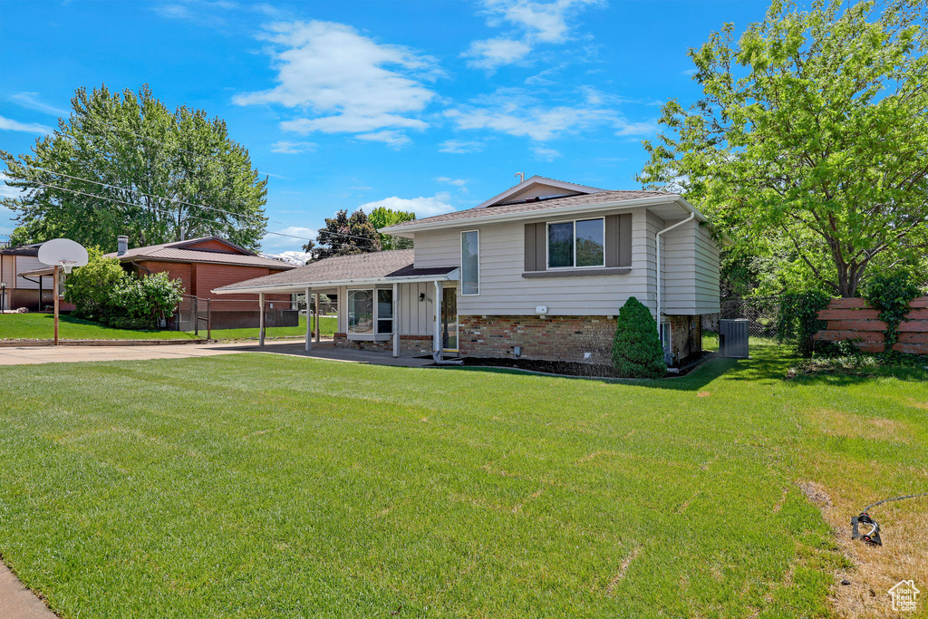 Split level home with central AC, brick siding, and roof with shingles