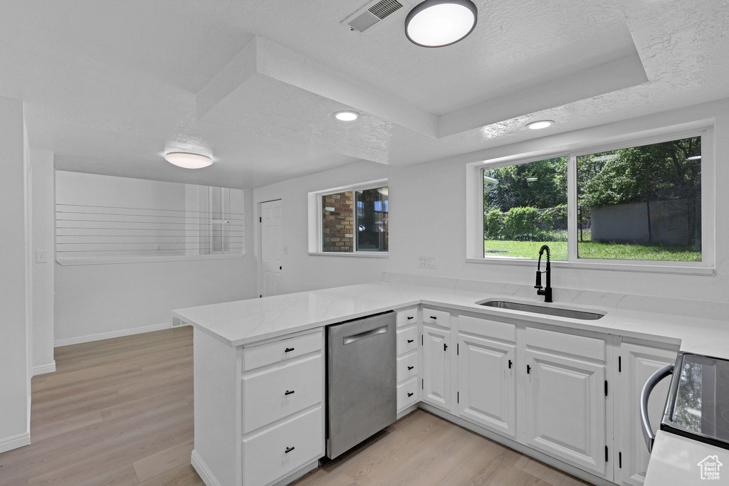Kitchen with stainless steel dishwasher, a sink, light wood-type flooring, a peninsula, and white cabinets