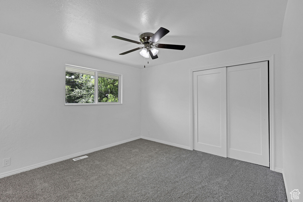 Unfurnished bedroom featuring carpet flooring, a ceiling fan, a closet, and baseboards