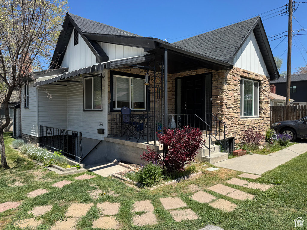View of front of home with board and batten siding, a shingled roof, and stone siding