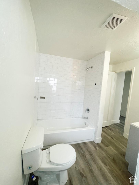 Bathroom featuring wood finished floors, toilet, washtub / shower combination, baseboards, and vanity