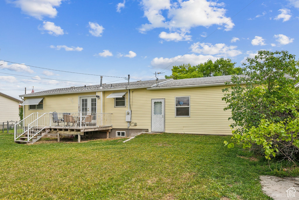 Rear view of house featuring a wooden deck and a yard