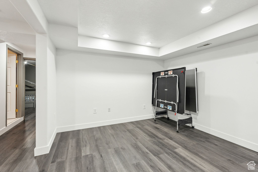 Unfurnished living room with wood finished floors, baseboards, recessed lighting, and a raised ceiling