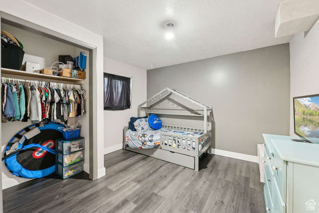 Bedroom featuring wood finished floors, baseboards, a closet, and a textured ceiling