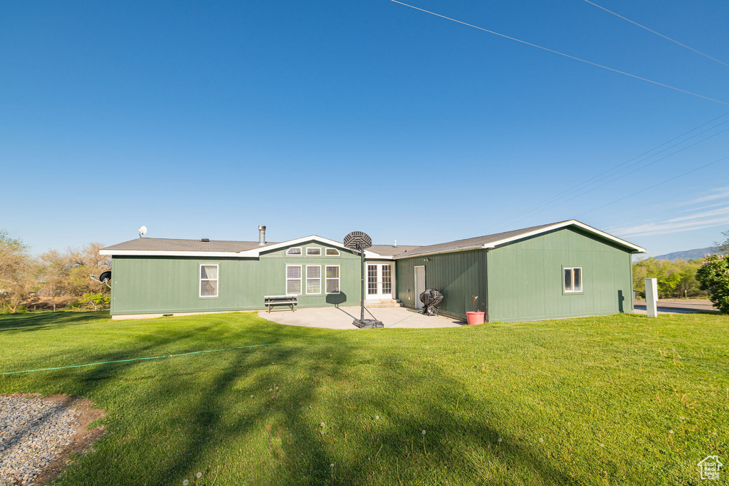 Rear view of property featuring french doors, a patio, and a yard