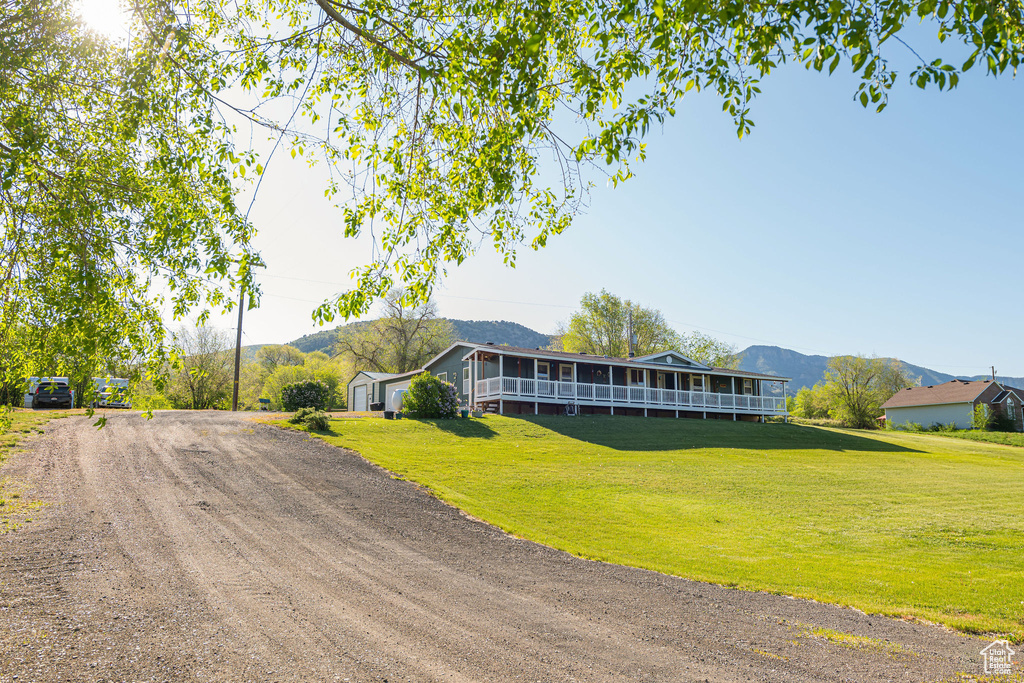 View of front of house featuring a front yard, a mountain view, and dirt driveway